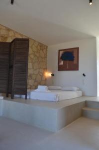 a bedroom with two beds and a stone wall at Kalypso Apartments in Kastríon