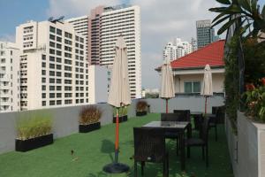 un patio en la azotea con mesas, sillas y edificios en Dazzle Residence, en Bangkok