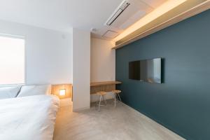 ein Schlafzimmer mit einer blauen Wand und einem TV darauf in der Unterkunft &AND HOSTEL AKIHABARA in Tokio