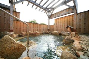 a hot tub with rocks in a wooden building at Mikasa in Nara