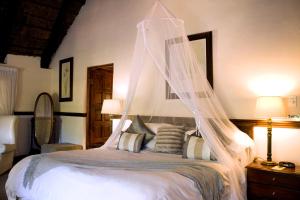 a bedroom with a bed with a mosquito net at Monchique Boutique Guest House in Muldersdrift