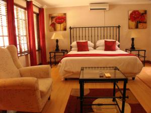 a bedroom with a bed and a couch and a table at Monchique Boutique Guest House in Muldersdrift
