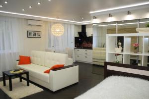 a living room with a white couch and orange pillows at Art Apartments in Volgograd