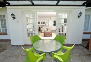eine Terrasse mit einem Glastisch und grünen Stühlen in der Unterkunft Lythwood Lodge in Lidgetton