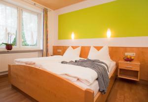 a bedroom with a large bed with a yellow wall at Landgasthof Am Sonnenhang in Vohenstrauß