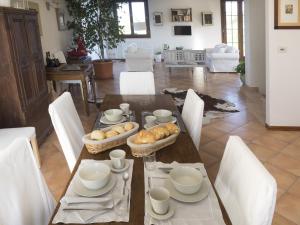 una mesa de comedor con sillas blancas y una mesa con comida. en Locanda Castel De Britti, en San Lazzaro di Savena