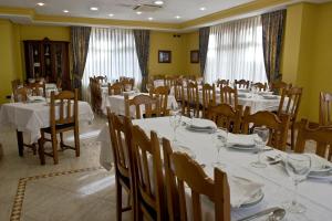 a dining room with white tables and chairs and windows at Hotel Doña Nieves in Noreña
