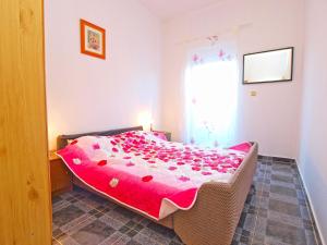 a bedroom with a bed with a pink comforter and a window at Apartments Ivo 1328 in Fažana