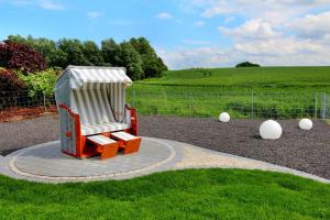 einen Spielplatz mit einem roten und weißen Stuhl im Gras in der Unterkunft Ferien-VILLA PACE in Göhren-Lebbin