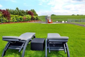 duas cadeiras sentadas na relva perto de um campo em Ferien_VILLA PACE em Göhren-Lebbin