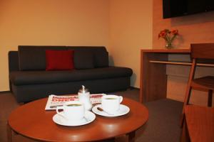 a living room with a table with two coffee cups on it at Hotel Toč in Lipova Lazne