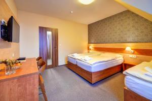 a hotel room with two beds and a desk at Hotel Toč in Lipova Lazne