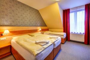 a hotel room with two beds and a window at Hotel Toč in Lipova Lazne