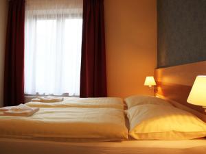 a bed with two pillows and a window at Hotel Toč in Lipova Lazne