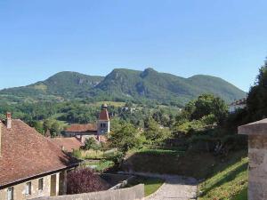 een dorp met een kerk en bergen op de achtergrond bij La maison de poupet in Salins-les-Bains