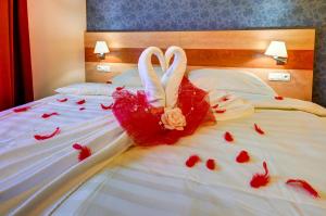 two swans dressed in red are sitting on a bed at Hotel Toč in Lipova Lazne