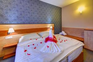 a bedroom with a bed with red rose petals on it at Hotel Toč in Lipova Lazne