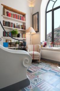 uma sala de estar com uma cadeira e uma estante de livros em Casa Buonocore em Positano