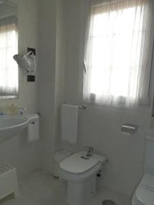 a white bathroom with a toilet and a sink at Hotel Doña Nieves in Noreña