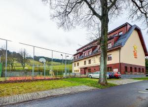 a building with a tree next to a fence at Hotel Toč in Lipova Lazne