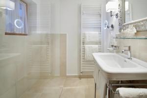 a white bathroom with a sink and a shower at Landsitz Römerhof - Hotel Apartments in Kitzbühel