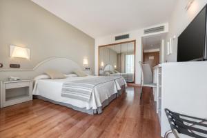 een witte slaapkamer met een bed en een spiegel bij VIK Gran Hotel Costa del Sol in La Cala de Mijas