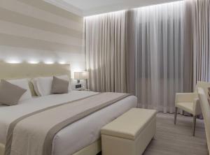 a white bedroom with a large bed and a chair at Hotel La Giocca in Rome