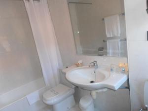 a white bathroom with a sink and a toilet at Hotel Doña Nieves in Noreña