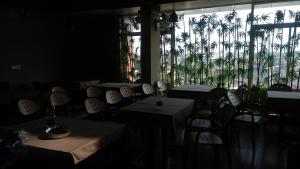 a dining room with tables and chairs and palm trees at Navaratna Palace in Belgaum