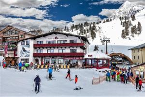 grupa osób jeżdżących na nartach przed domkiem narciarskim w obiekcie Austria Alpinhotel Ski IN Ski OUT an der Edelweissbahn w mieście Obertauern