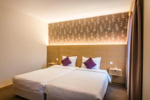 ein Schlafzimmer mit einem großen weißen Bett mit lila Kissen in der Unterkunft Hotel Bon Repos in Scheidgen