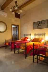 a bedroom with three beds with red and orange sheets at Maltese Town House Sliema in Sliema
