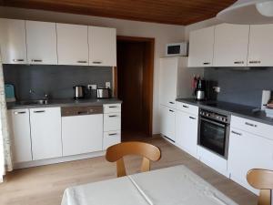 a kitchen with white cabinets and a table at Gästehaus Steininger in Zwiesel