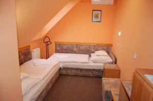 2 camas en una habitación con paredes de color naranja en Judit Panzio, en Gyulakeszi