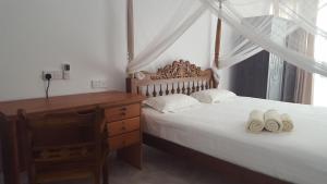 a bedroom with a desk and a bed with towels at Edelweiss Resort in Mirissa