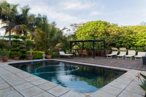 a swimming pool with chairs and a table in a yard at The Villa Salt Rock in Ballito