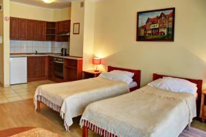 a hotel room with two beds and a kitchen at Apartamenty & Restauracja Janus in Ełk
