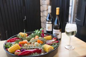 a bowl of vegetables on a table with a glass of wine at Apartments " Happy villa " in Splitska