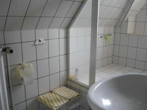 a white tiled bathroom with a sink and a shower at Ferienwohnung Doelling in Ausacker