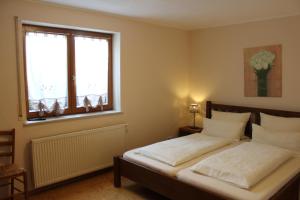 Schlafzimmer mit einem Bett mit weißer Bettwäsche und einem Fenster in der Unterkunft Gästehaus Kril in Rust