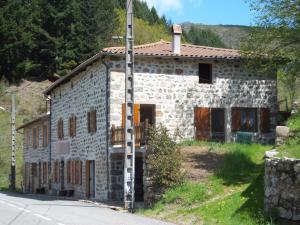 une maison en pierre avec une échelle devant elle dans l'établissement Gîte-La Combelle, à Dornas