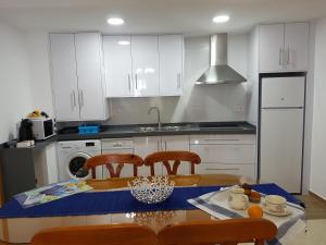 a kitchen with white cabinets and a table and chairs at Apartamento centrico in Almuñécar