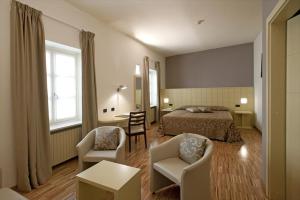 a bedroom with a bed and two chairs and a table at Albergo Ristorante Badellino dal 1917 in Bra
