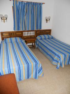 duas camas num quarto com riscas azuis e amarelas em Apartamentos Los Juncos II em Playa del Inglés