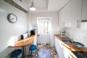 uma cozinha com um lavatório e um relógio na parede em FLH Fresh and Cozy Old Town Duplex em Lisboa
