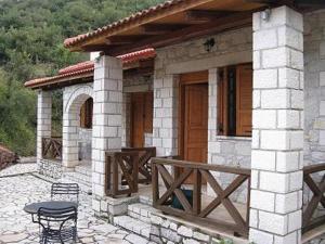 mały kamienny dom ze stołem i werandą w obiekcie Lithos w mieście Sirmbáni