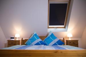 una camera da letto con un letto con cuscini blu e una finestra di Ferienwohnung Am Sonnenhang a Neualbenreuth