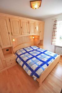 a large bed in a room with wooden cabinets at Appartamenti Pollam in Pozza di Fassa