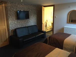 a hotel room with a couch and a tv on a wall at Lodge at Lochside in Bridgend of Lintrathen
