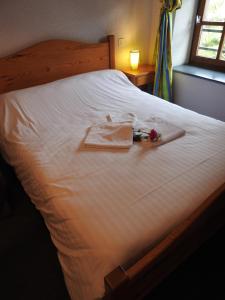 
a bed with a white blanket and pillows on top of it at Aux Globe Trotters in Murat
